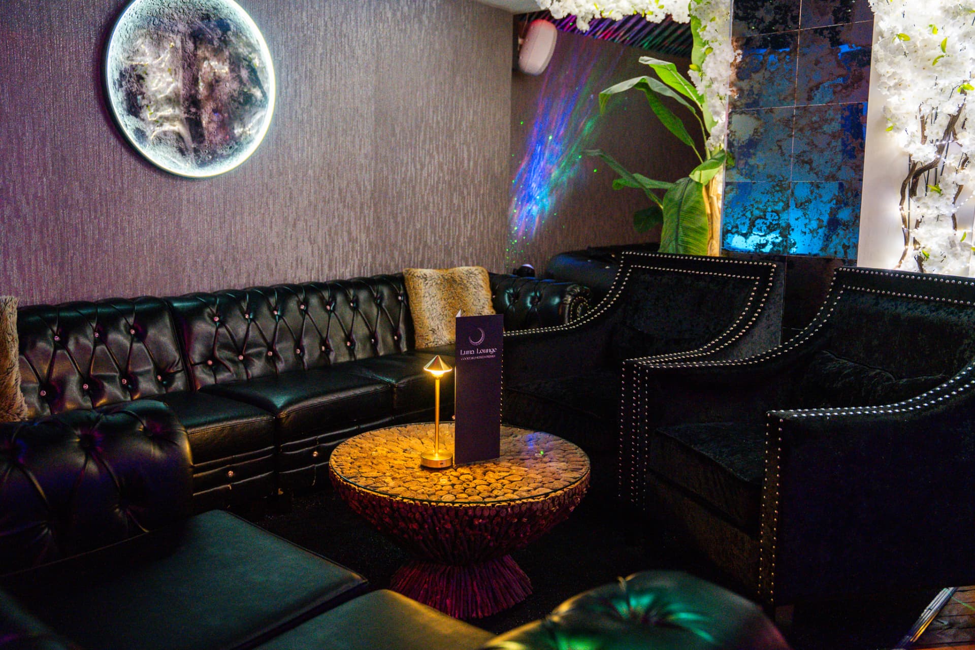 Luna Lounge seating with black leather sofas and moon wall art