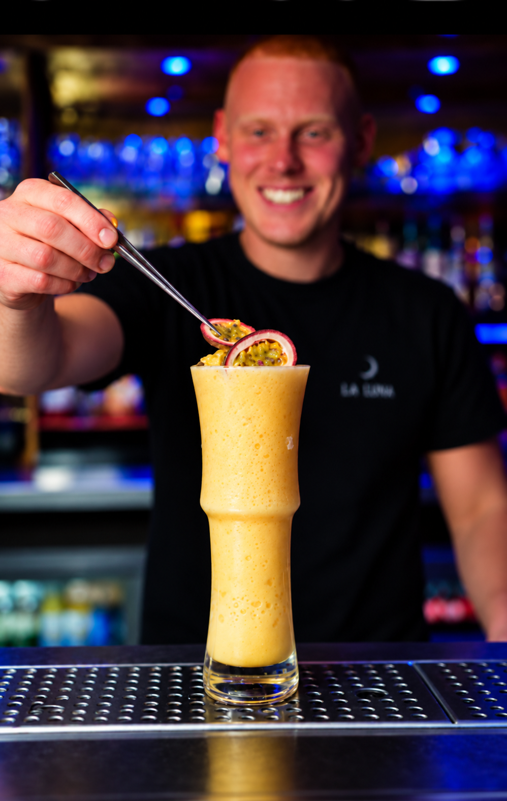 A bartender garnishing a passionfruit cocktail at the bar for Luna Rossa events