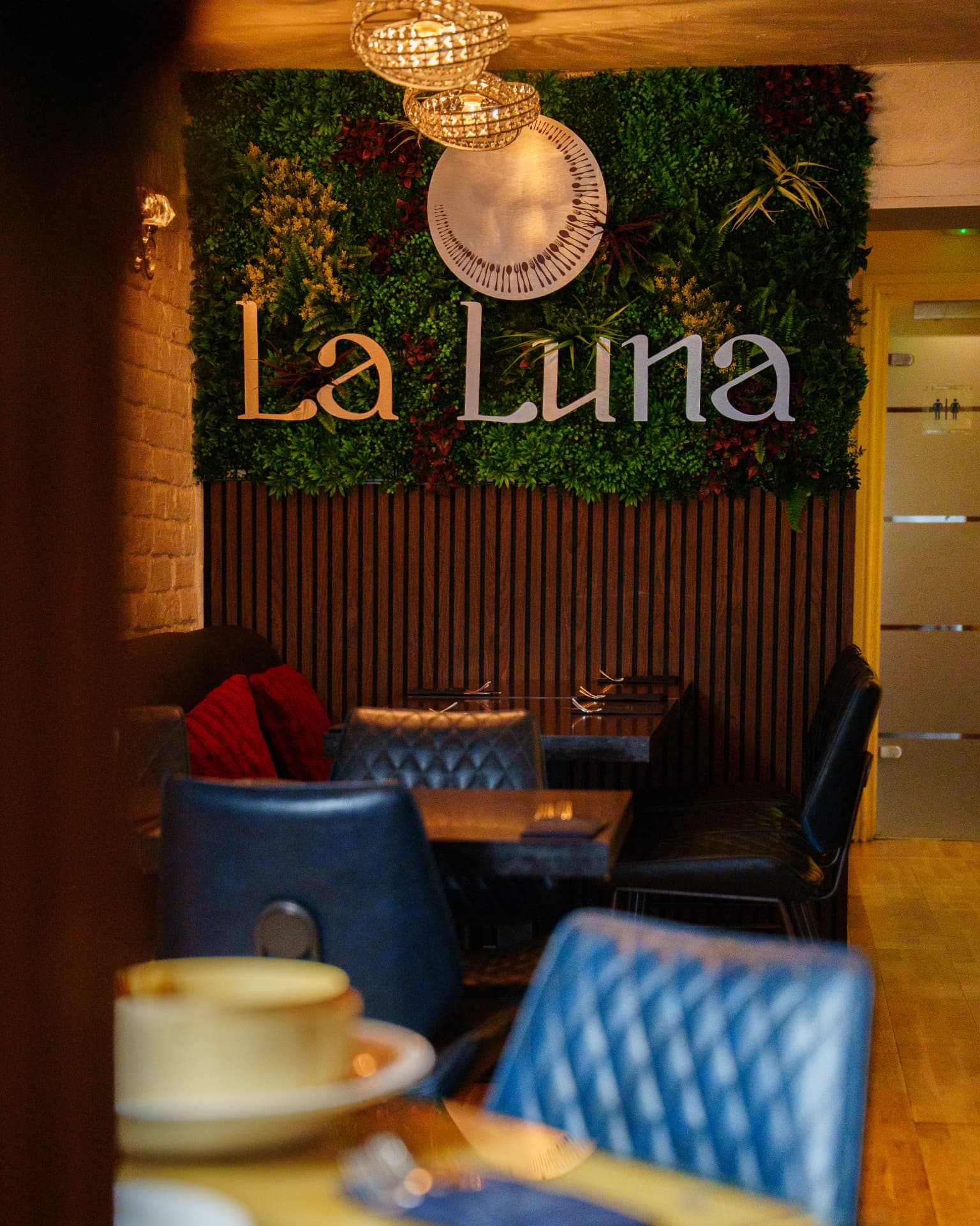 La Luna dining area with foliage wall signage and chandelier