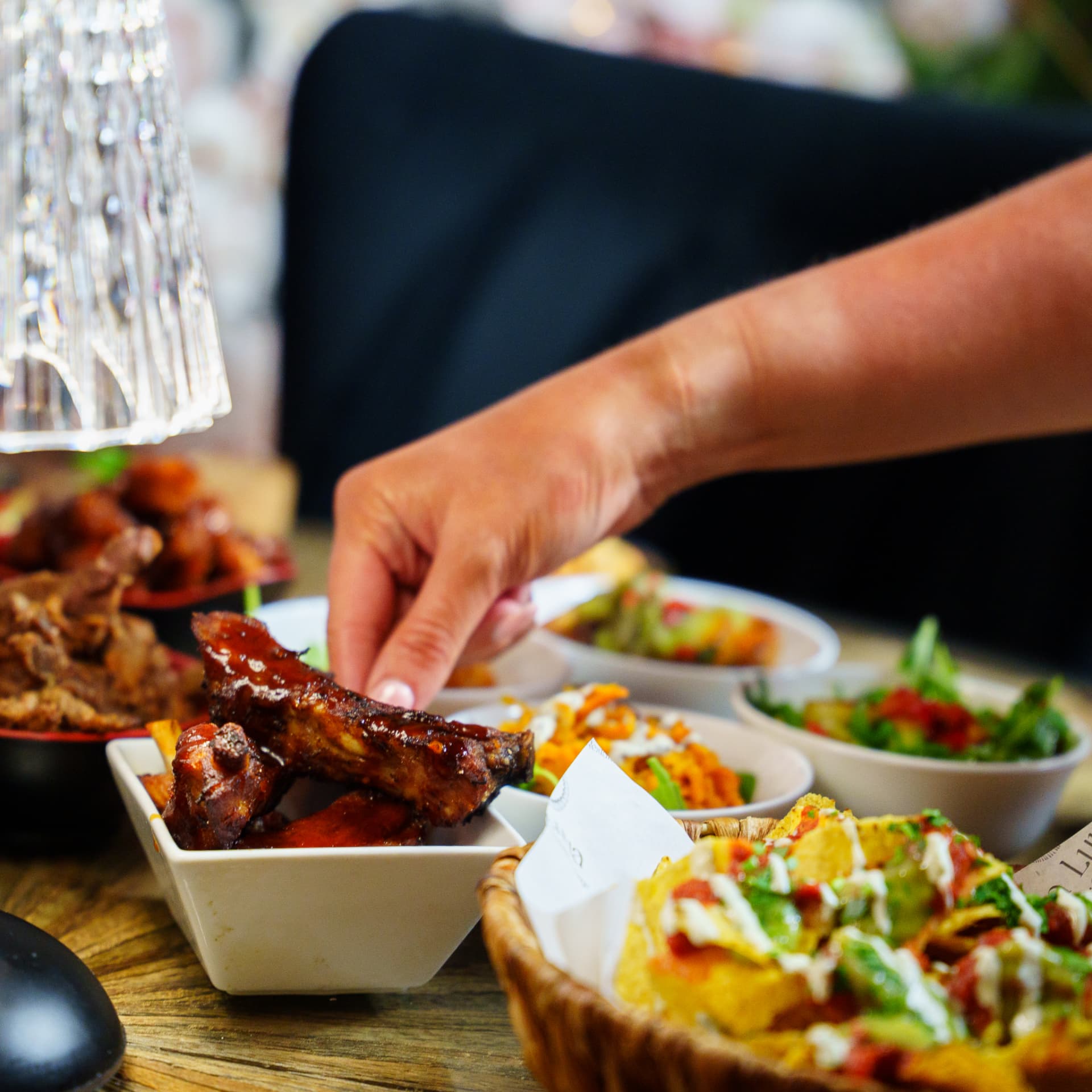Hand reaching for sticky ribs on a sharing tapas spread